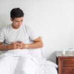 man-sits-bed-with-stomachache-presses-his-stomach-with-his-hands