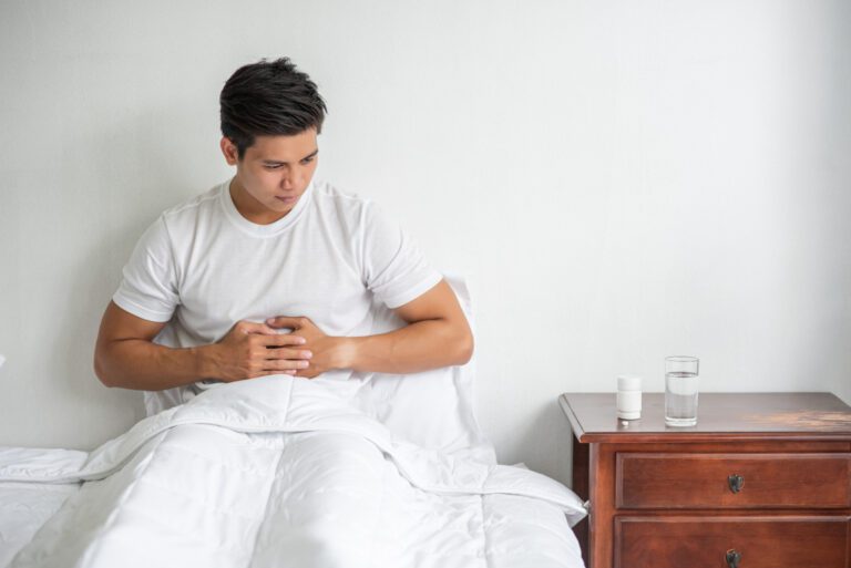 man-sits-bed-with-stomachache-presses-his-stomach-with-his-hands
